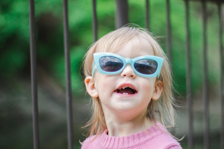 a little girl wearing blue sunglasses with a smile