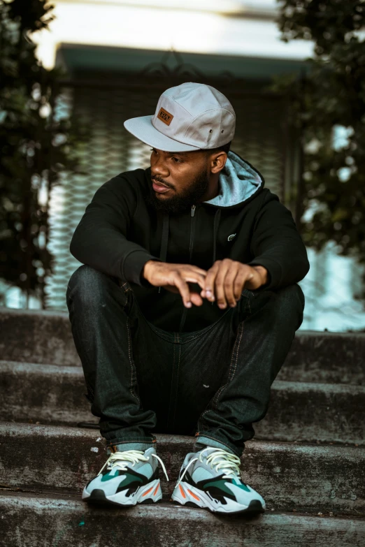 a black man sitting down with his hands on his knees