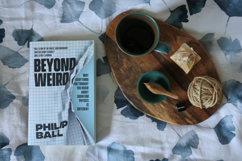 a book on the bed next to a cup of coffee