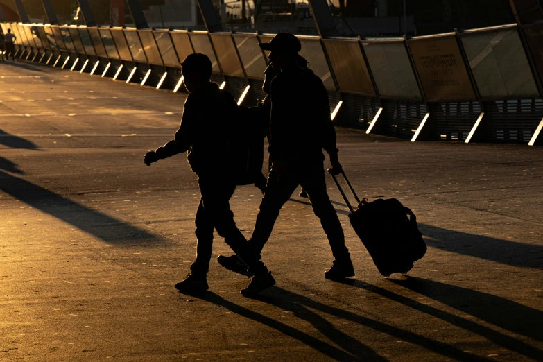 two people are walking and one is pulling a luggage case