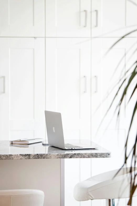 the interior of a kitchen with an apple laptop on the counter