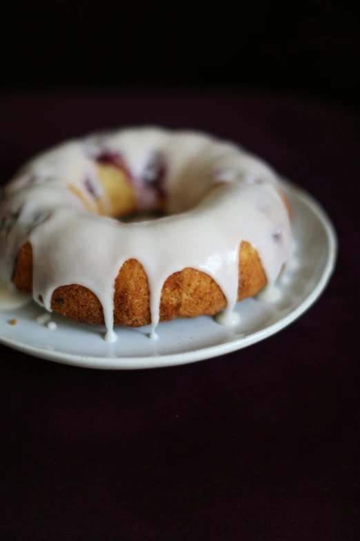 a bunt cake on a white plate on a purple tablecloth