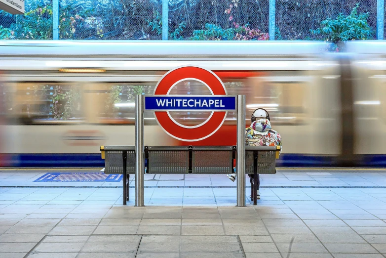 a train on a track behind a sign and bench