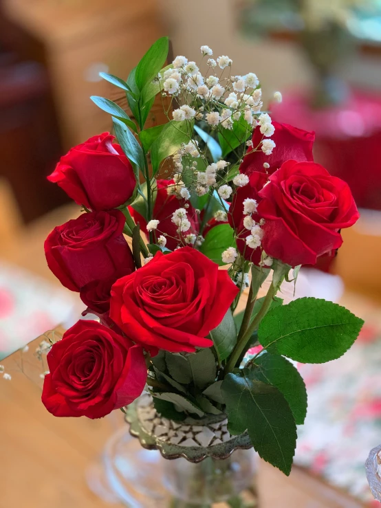 a vase filled with red roses and white baby's breath