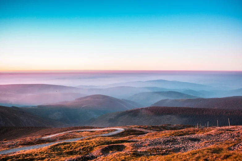 a hillside has mountains covered in mist and fog