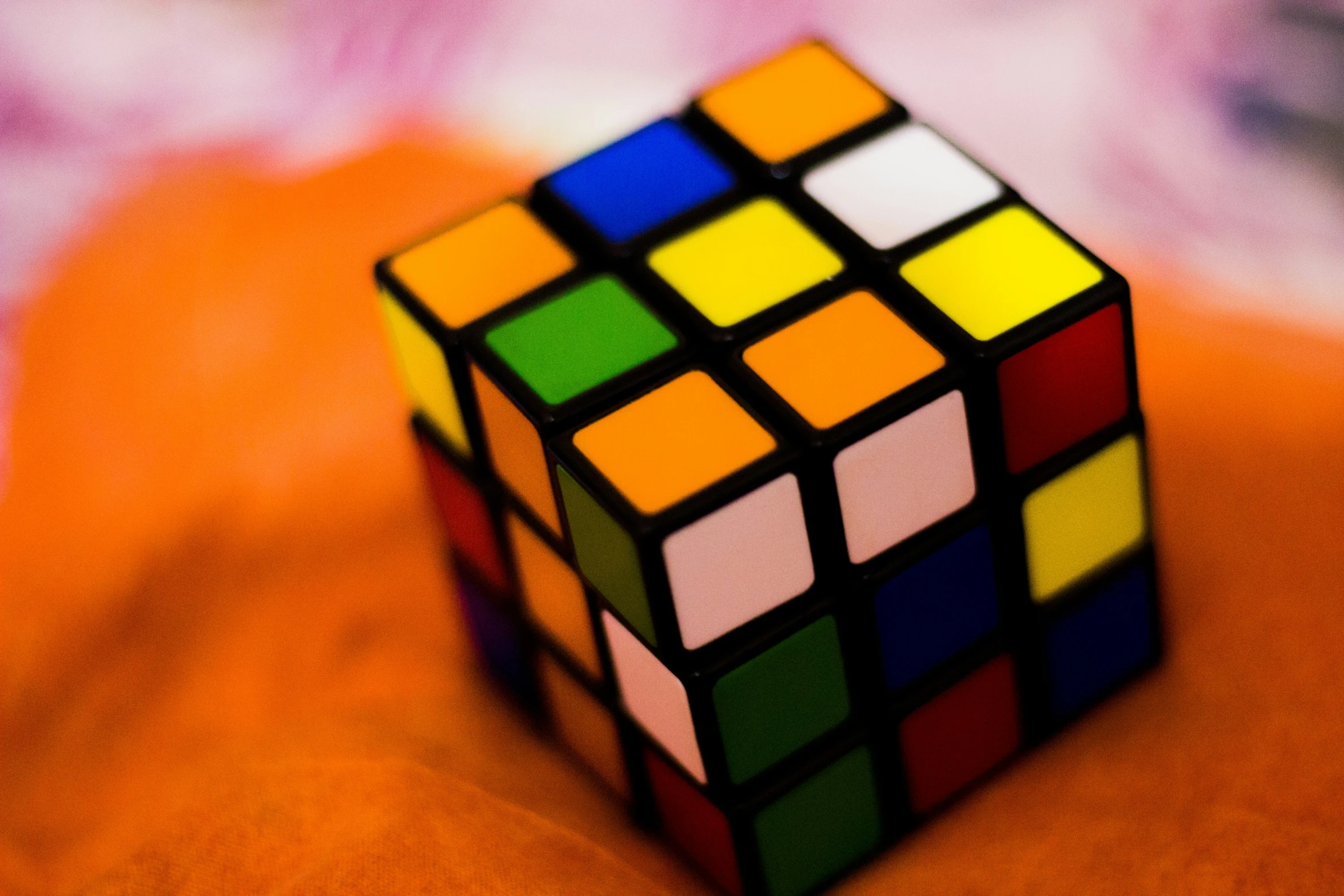 colorful cube sitting on orange surface with blurred background