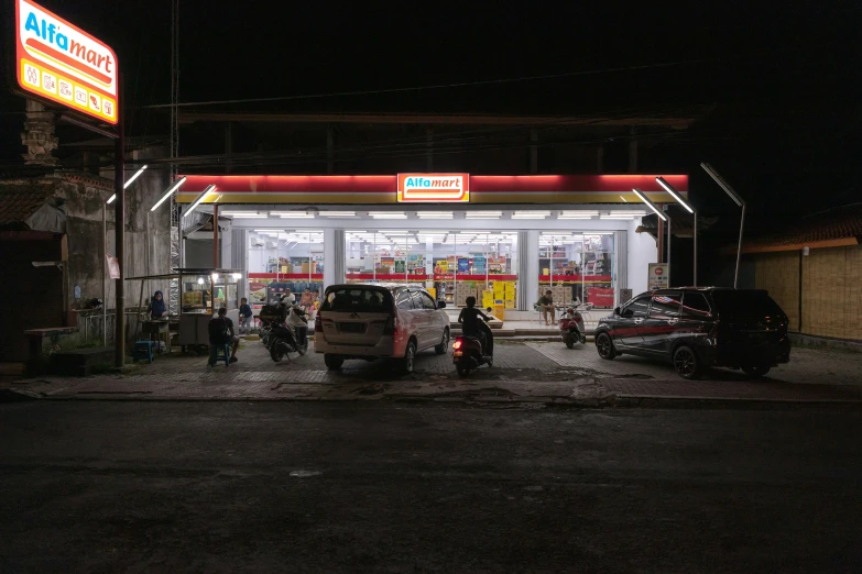 a gas station at night time with some cars parked in front