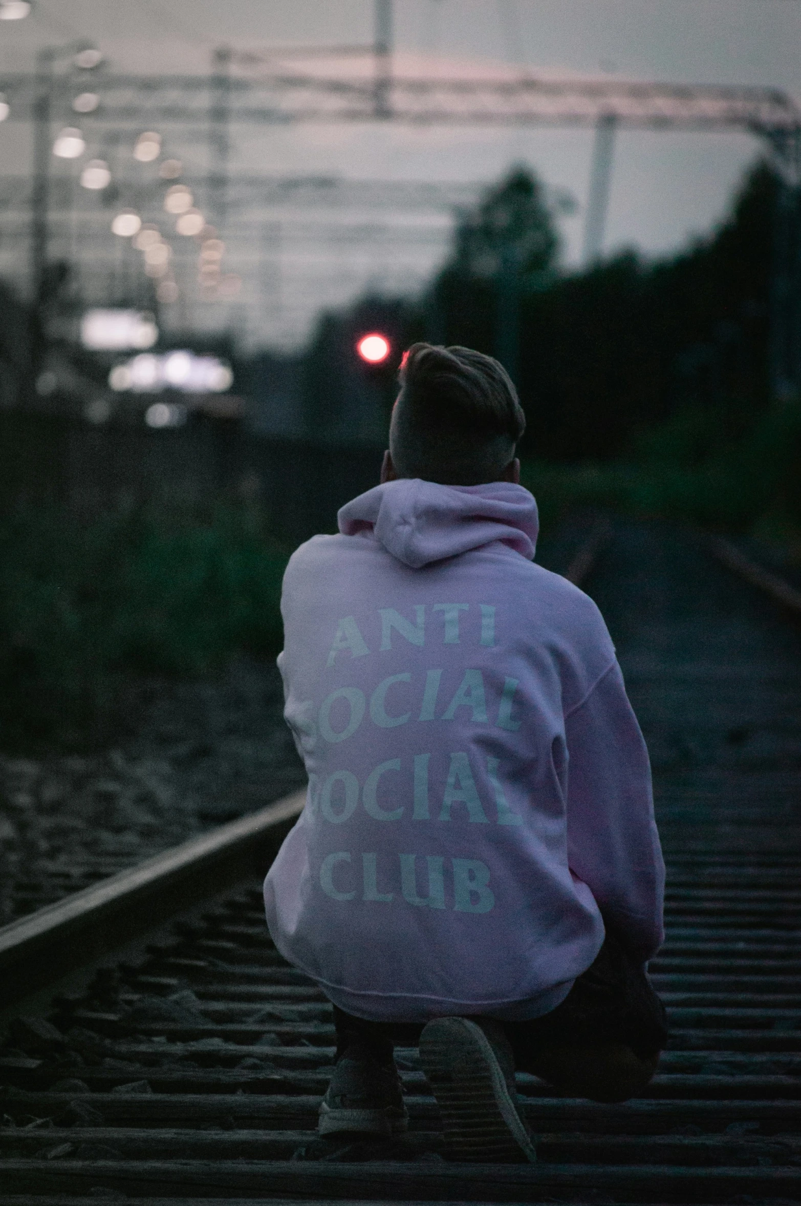 a person sitting down and facing the train tracks