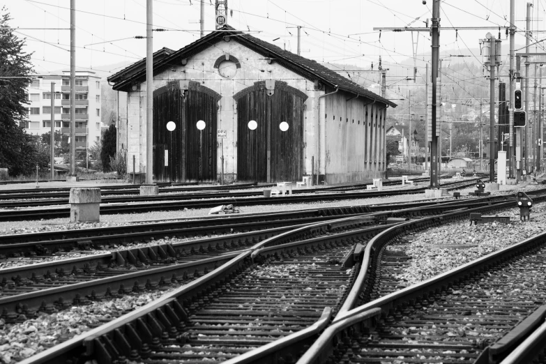 a lone person stands on a platform near railroad tracks