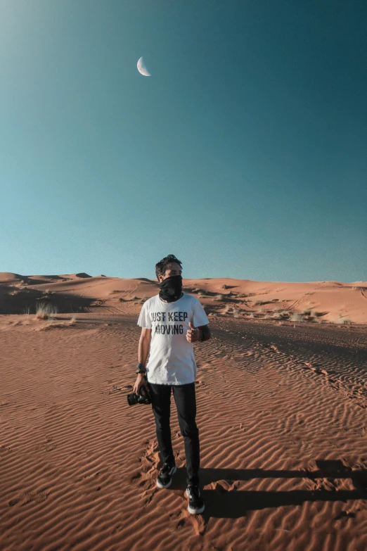 a man standing on the desert with a camera in his hand