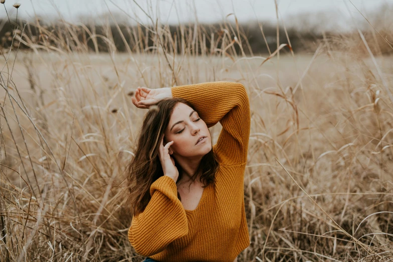 woman in a field wearing a yellow sweater and black pants