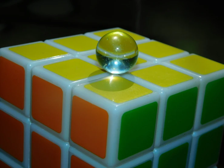 a glass sphere placed on top of an odd cube