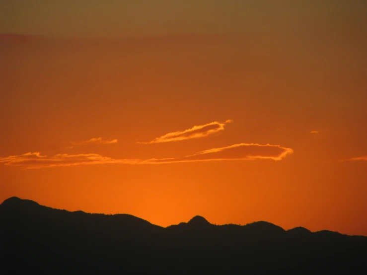 a plane is flying in a sunset over a mountain range