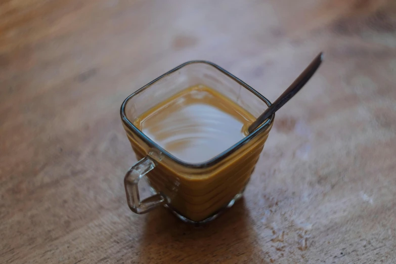 a cup with a spoon in it sitting on a wooden table