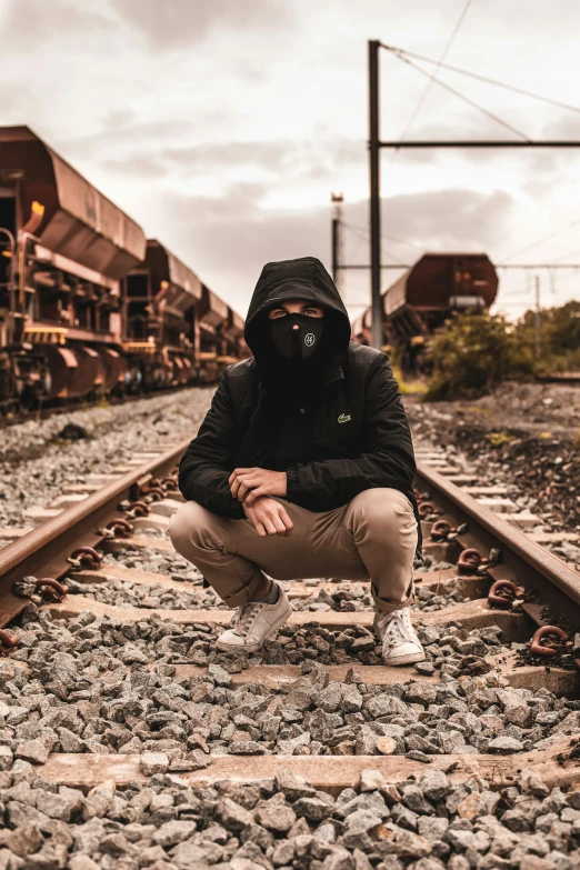 a person squatting down on railroad tracks