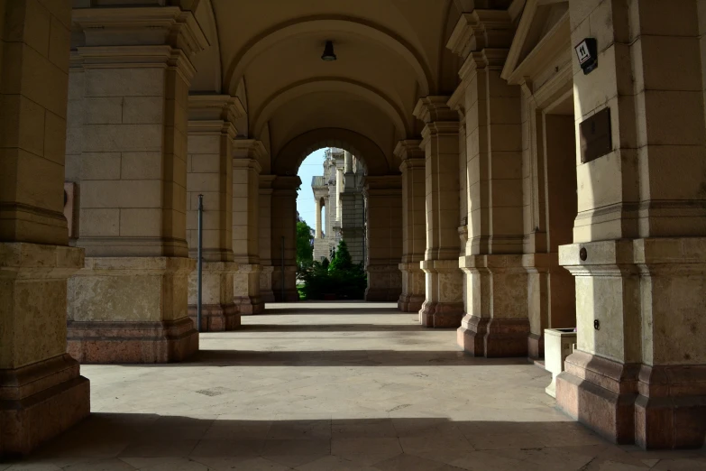 a walkway lined with beige columns and stone pillars