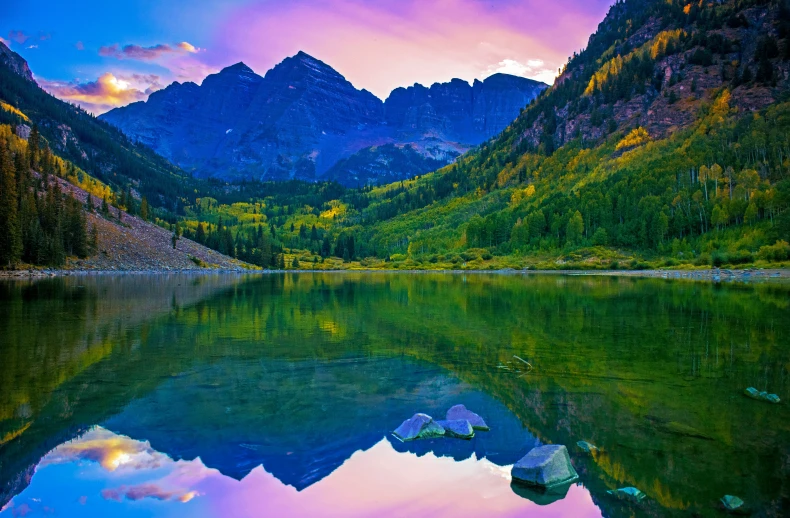 the view of a lake that is still surrounded by mountains