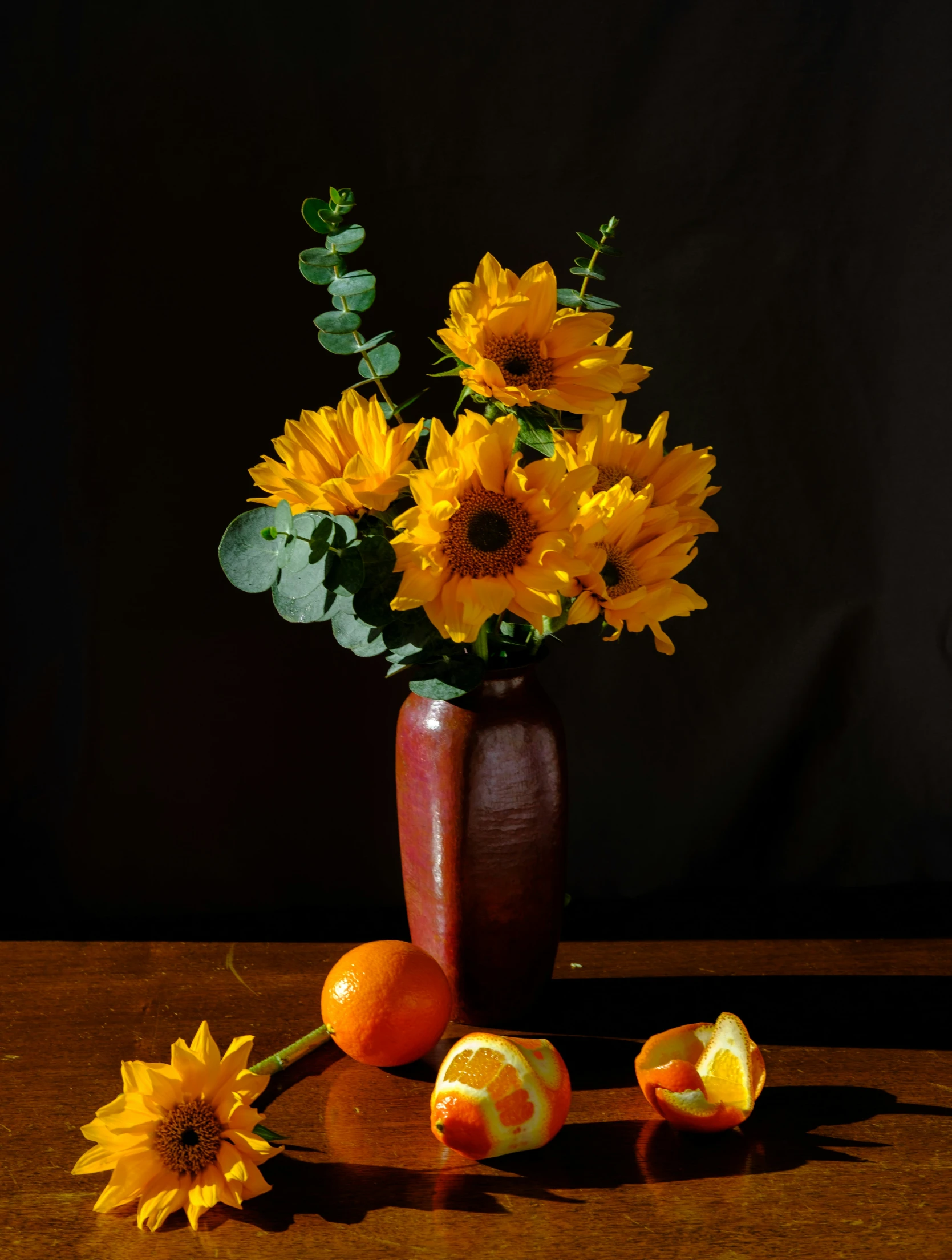 some sunflowers are in a vase, along with fruits and a flower arrangement