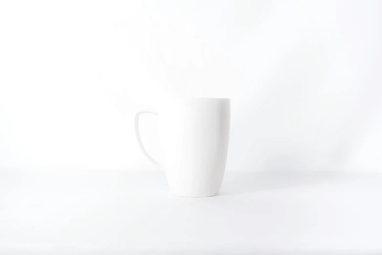 a tall white mug is on a plain background