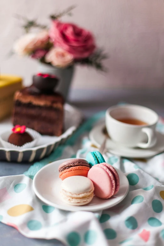 a table topped with two different types of macarons and cup of tea