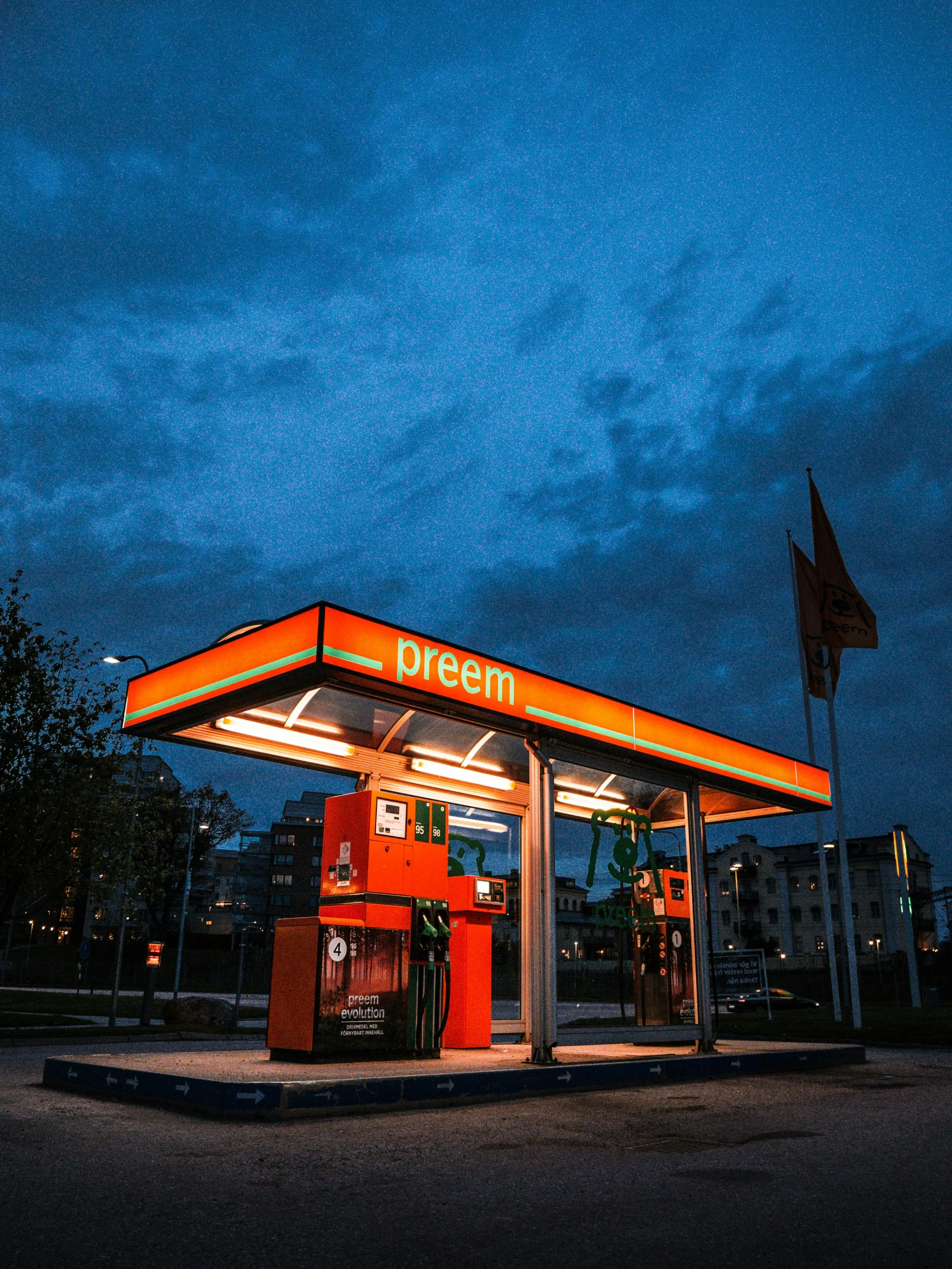 a orange and red gas station lit up in the evening