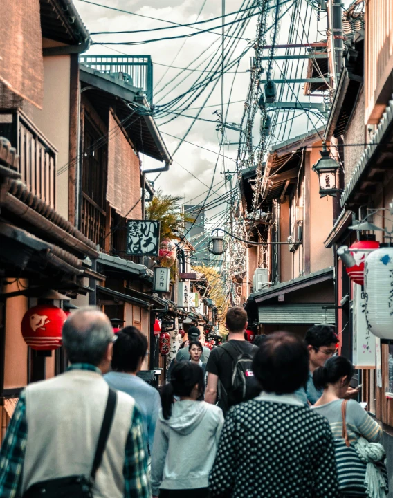 people walking down an alley with wires overhead