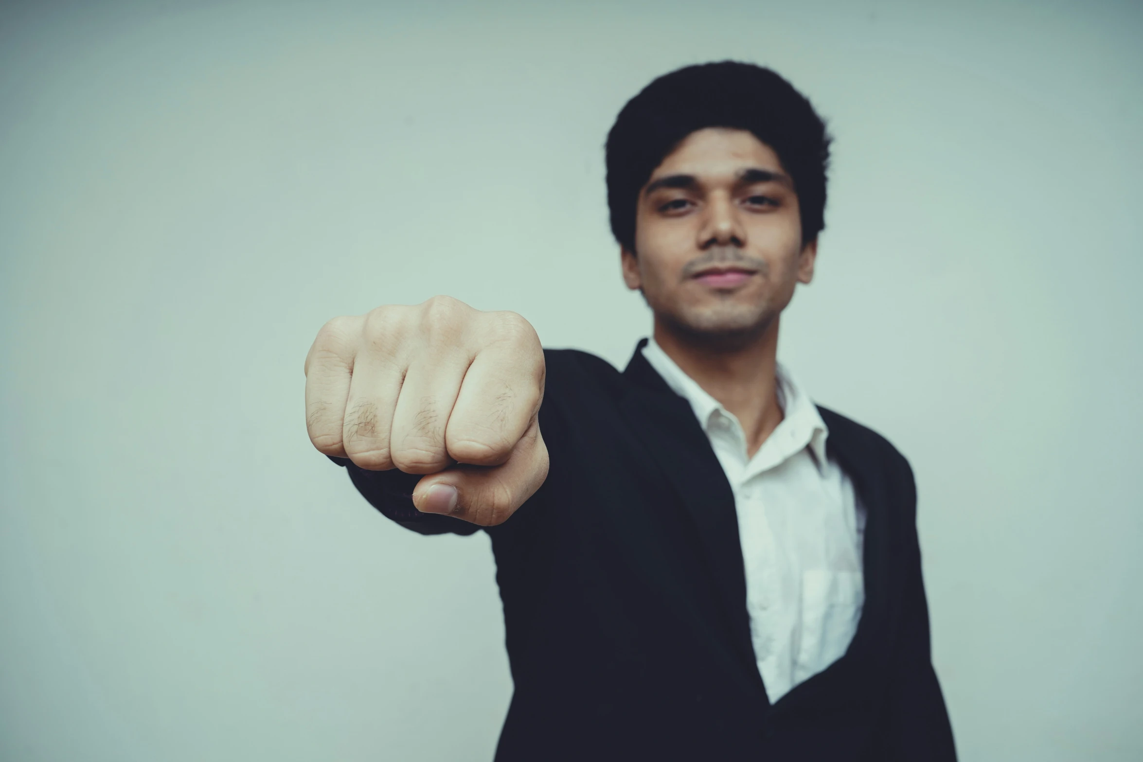 the man is dressed in a business suit and pointing at soing with his fist