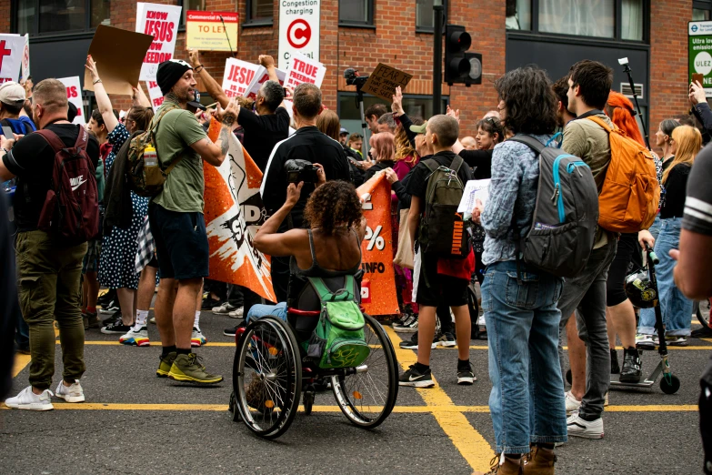 a woman in a wheelchair being blocked by protesters