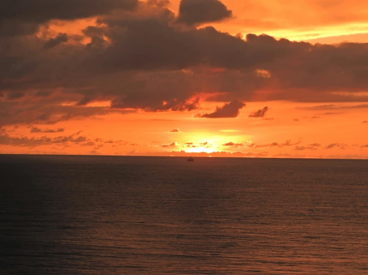 the sun is setting on the horizon of the ocean