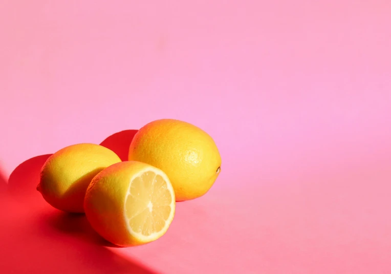 three lemons are next to each other on a pink background