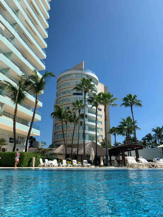 the pool at an outdoor el with lounge chairs and palm trees