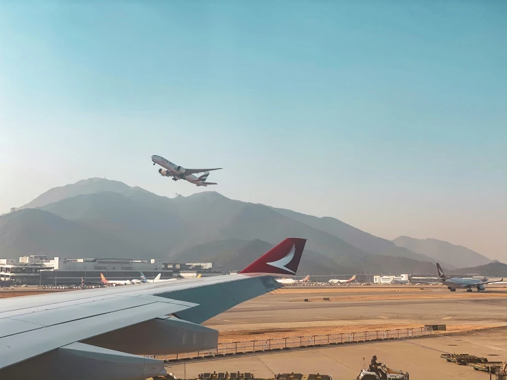 an airplane is flying over several planes parked near each other