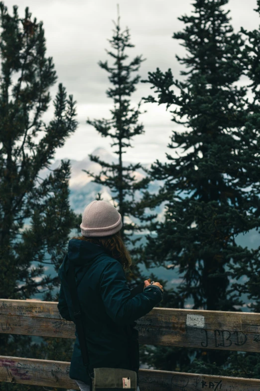 a woman in winter clothing standing on a wooden deck