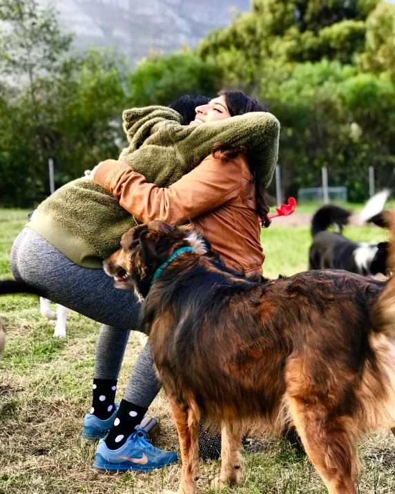 a person that is hugging a dog in a field