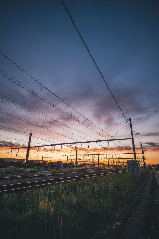 the sky is very cloudy as a train passes under power lines