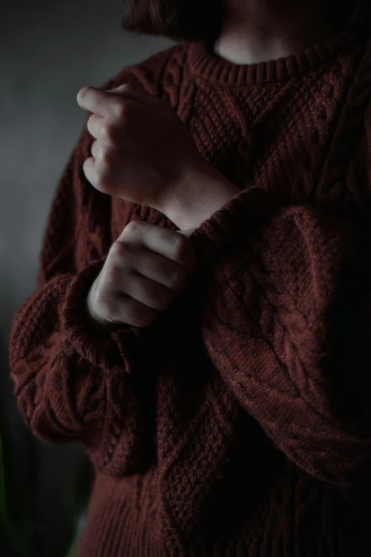 a girl wearing a sweater with her hands together