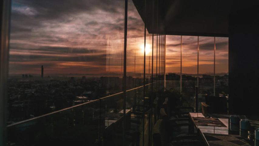 a sunset seen through a glass balcony over a city