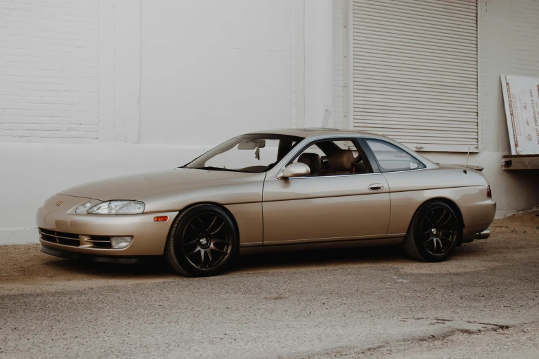 a gold honda car in front of a white wall