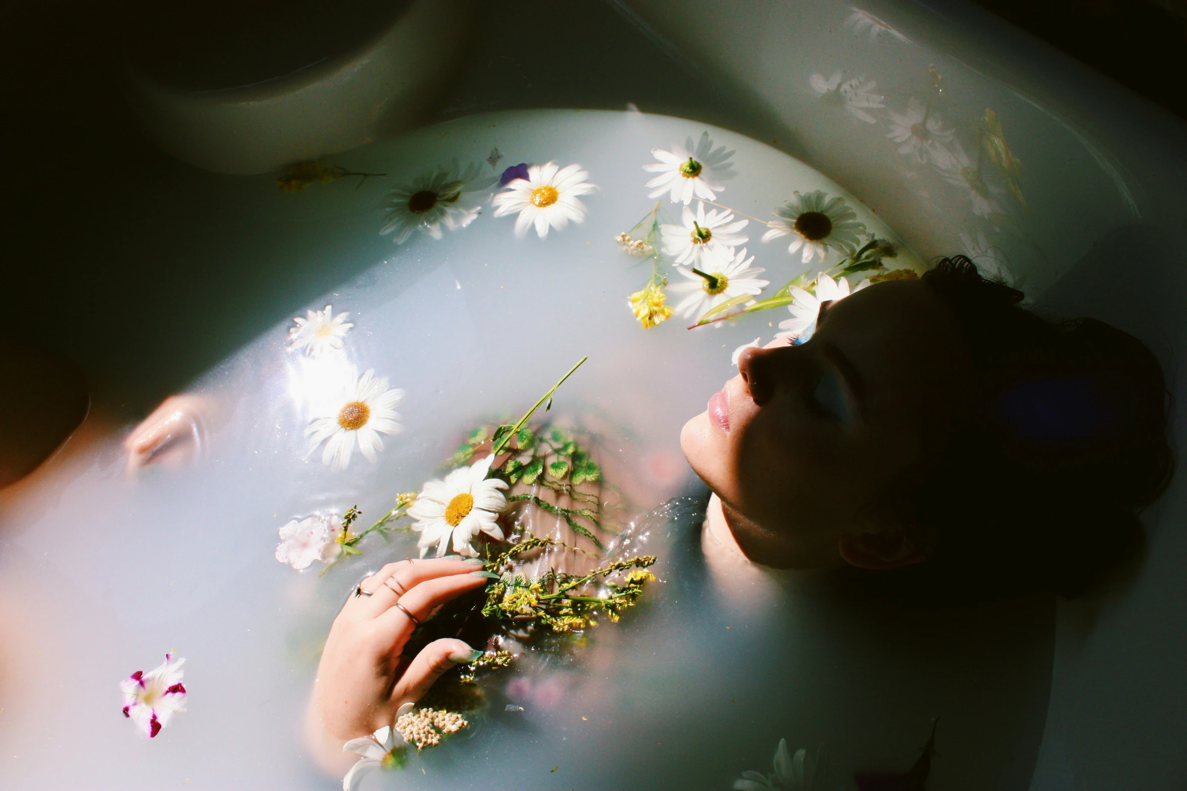 a man is lying down in the bath tub with daisies