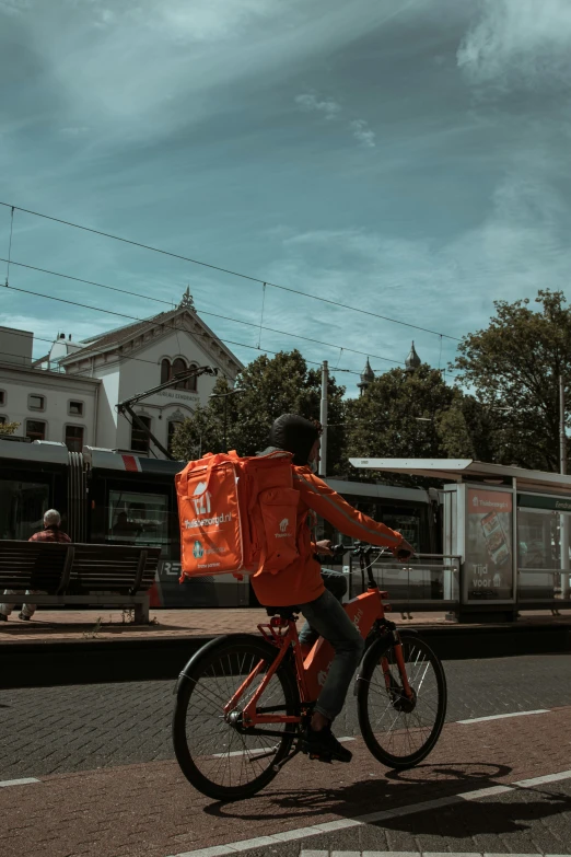 an orange backpack strapped to a bicycle in front of a train