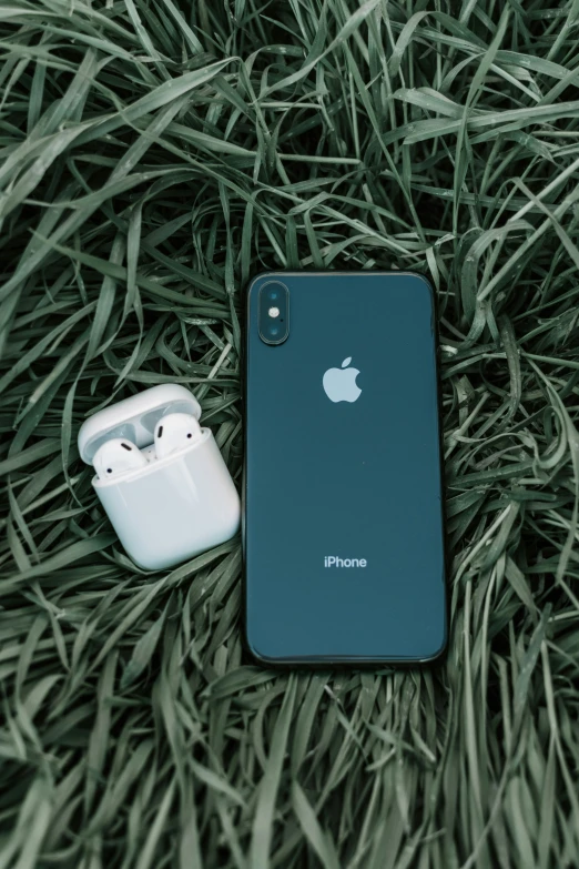 an apple earpods and an iphone laying in the grass