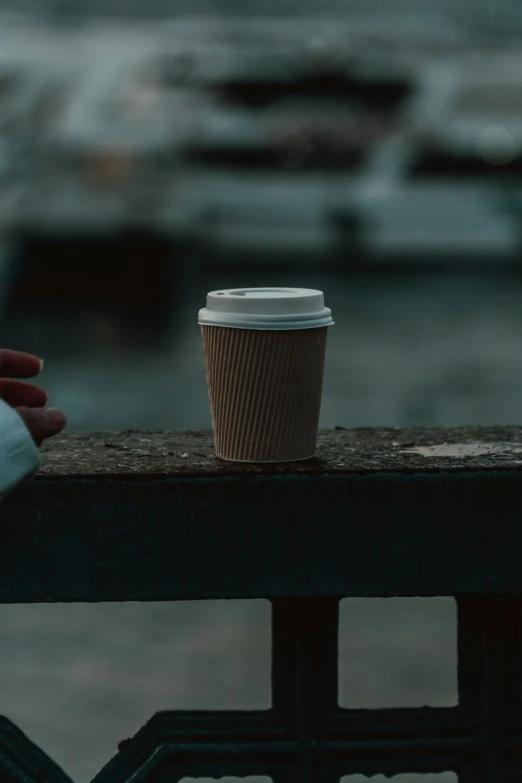 someone holding their arm over the railing as they hold a coffee cup