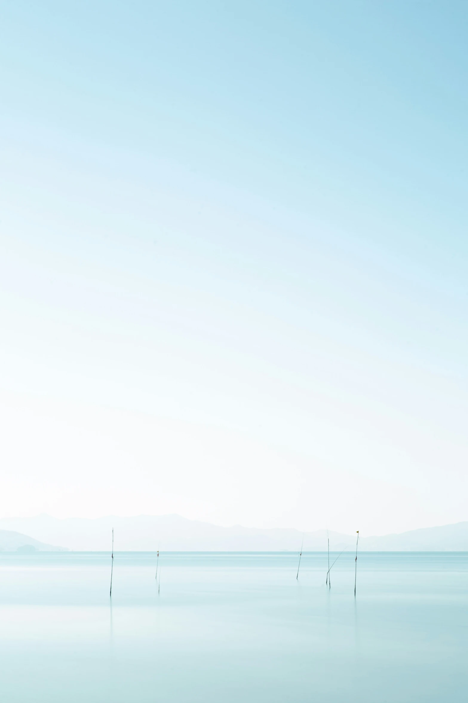 several poles in water with mountains in the background