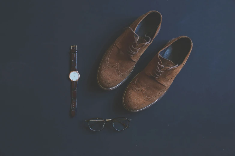 a pair of shoes, a watch and glasses on a surface