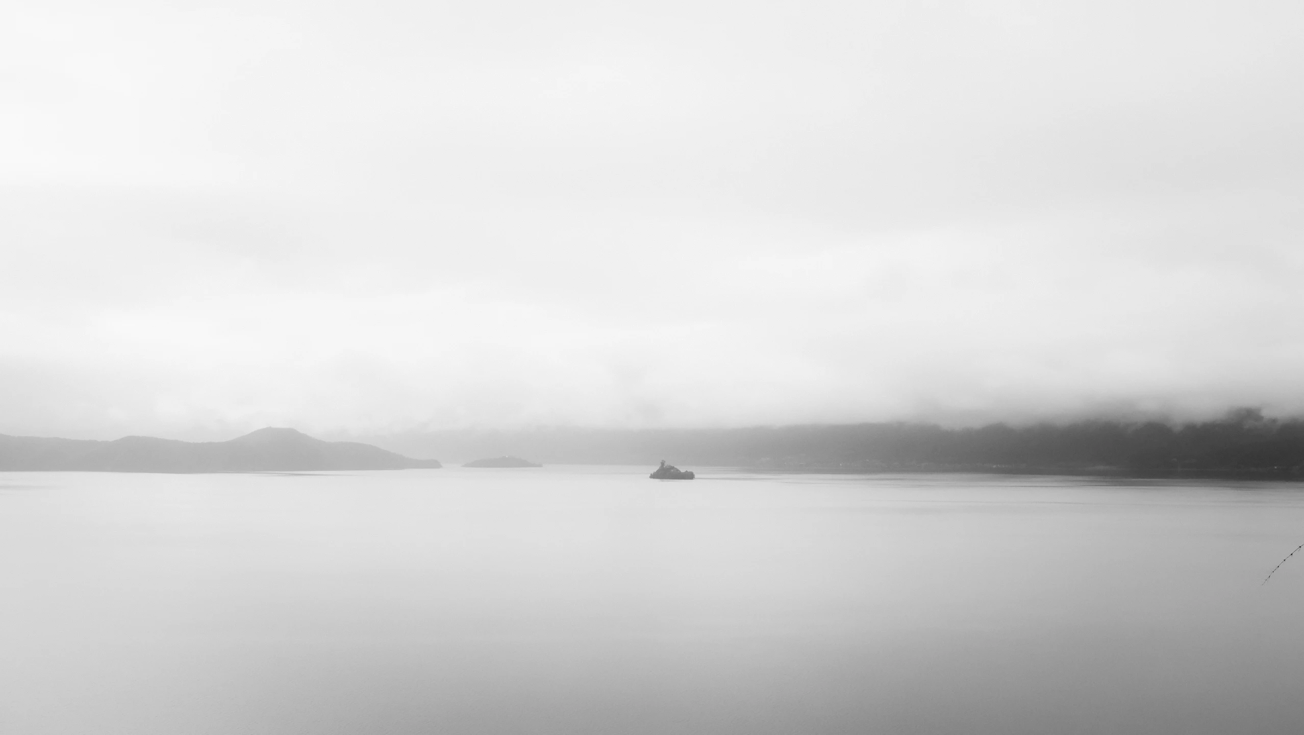 a boat travels across a foggy bay on a foggy day