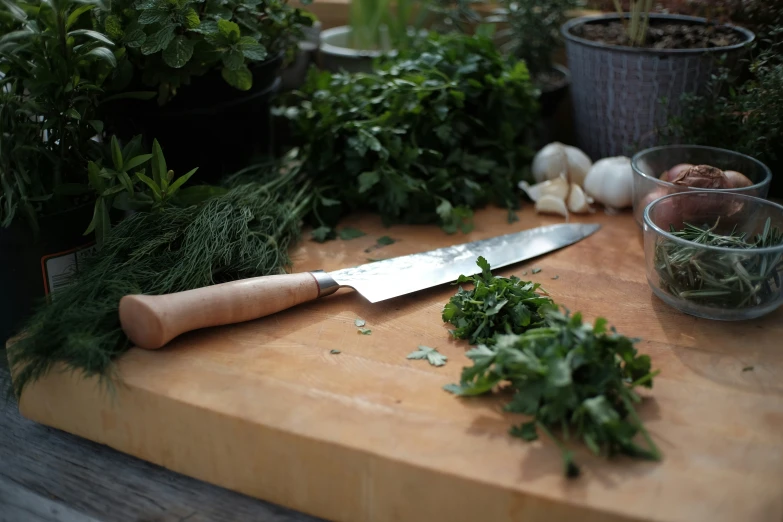 a knife on a board next to some herbs