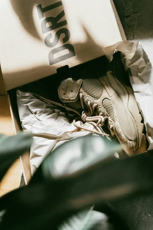 an open shoe box filled with a sneaker and the top half covered in fabric