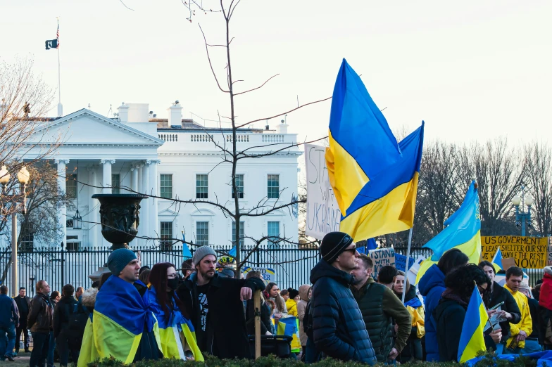 some people holding a sign and flag with a building in the background