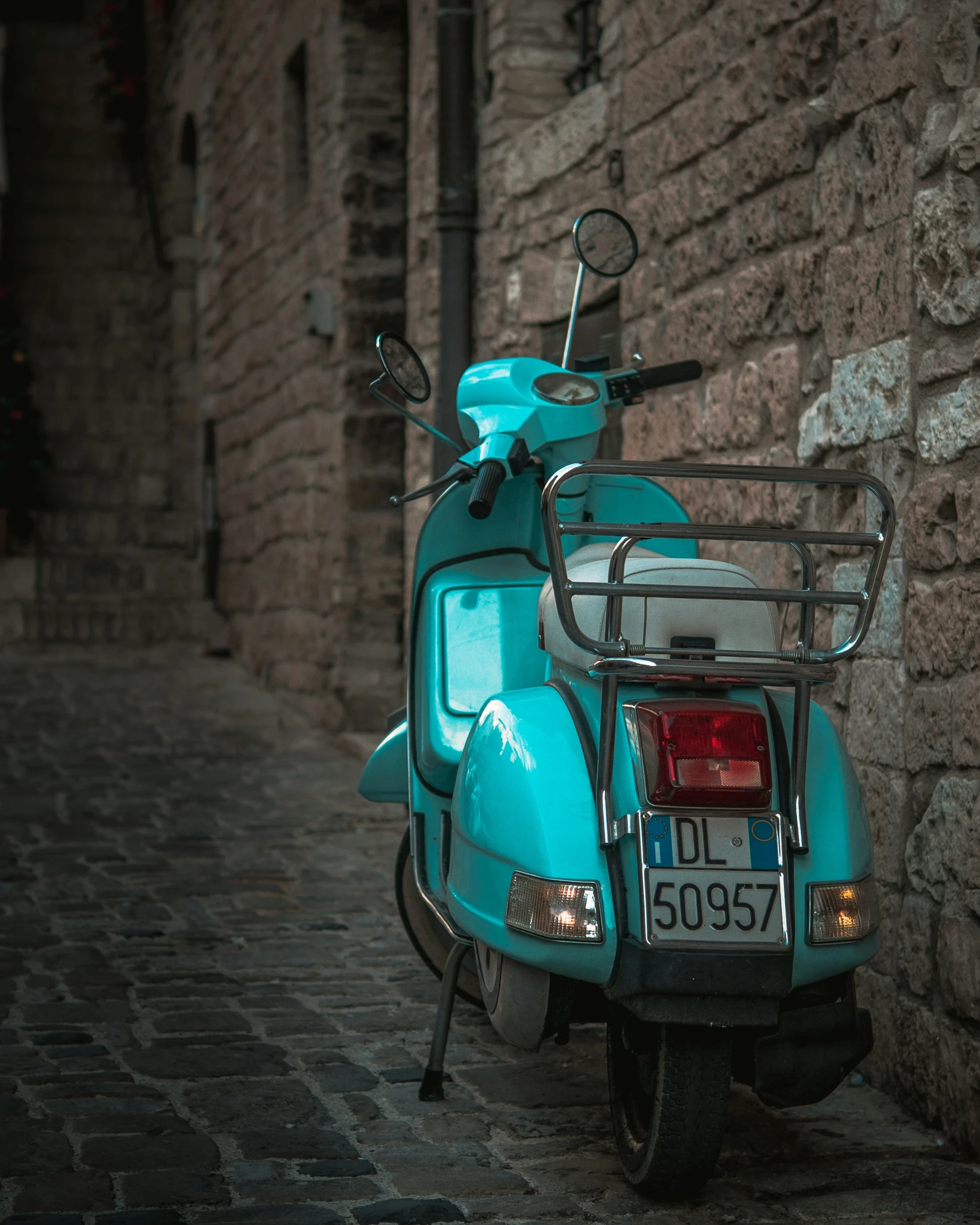 there is a light blue moped parked on the side of the street