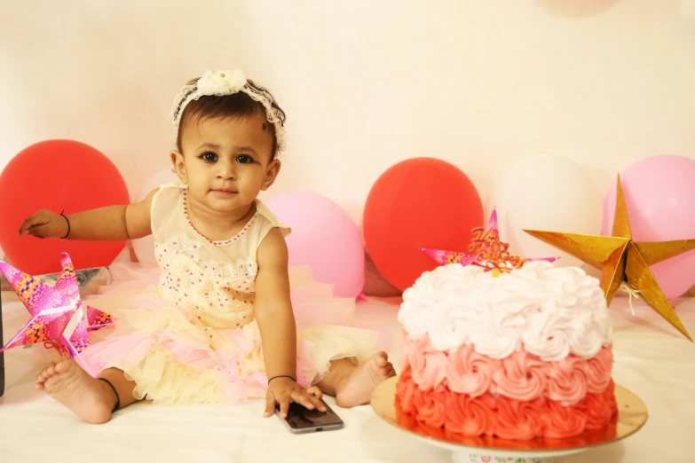 baby sitting next to birthday cake with a bottle of wine